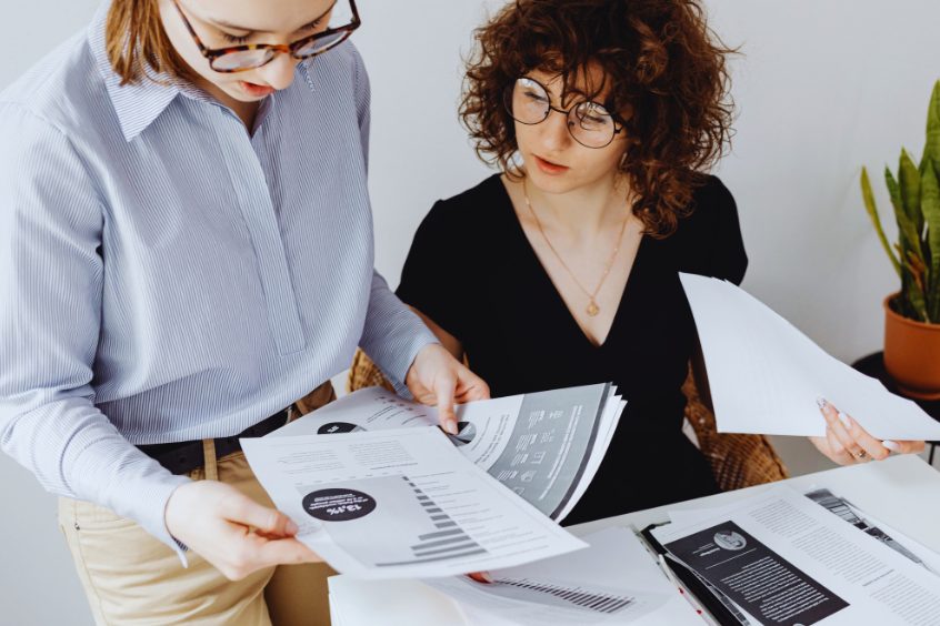 Two women reviewing documents together at a table in the office