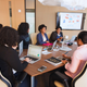 Women are seated around a conference table during a business meeting