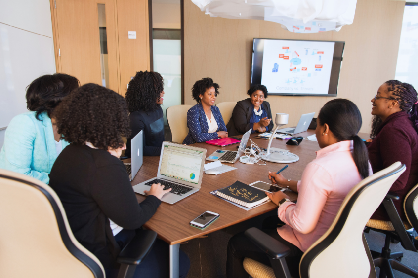 Women are seated around a conference table during a business meeting