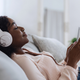 Woman relaxing at home listening to music on her phone