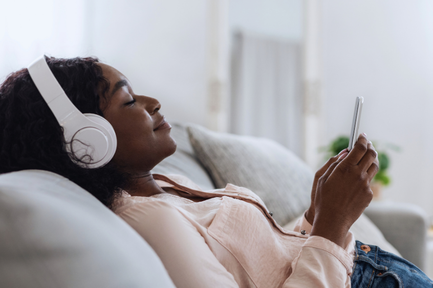 Woman relaxing at home listening to music on her phone