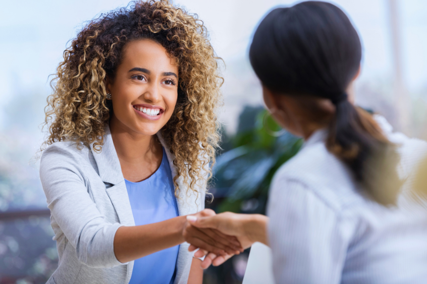 A young woman meeting her therapist smiling and shaking hands 
