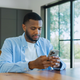 Man sitting at a wooden table intently browsing or checking messages on his mobile phone