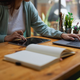 Woman taking notes in her notepad while learning on laptop
