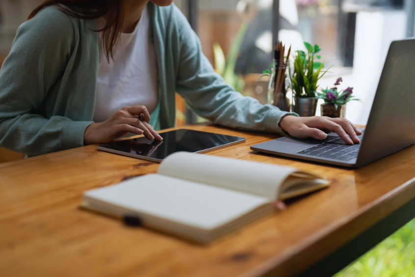 Woman taking notes in her notepad while learning on laptop