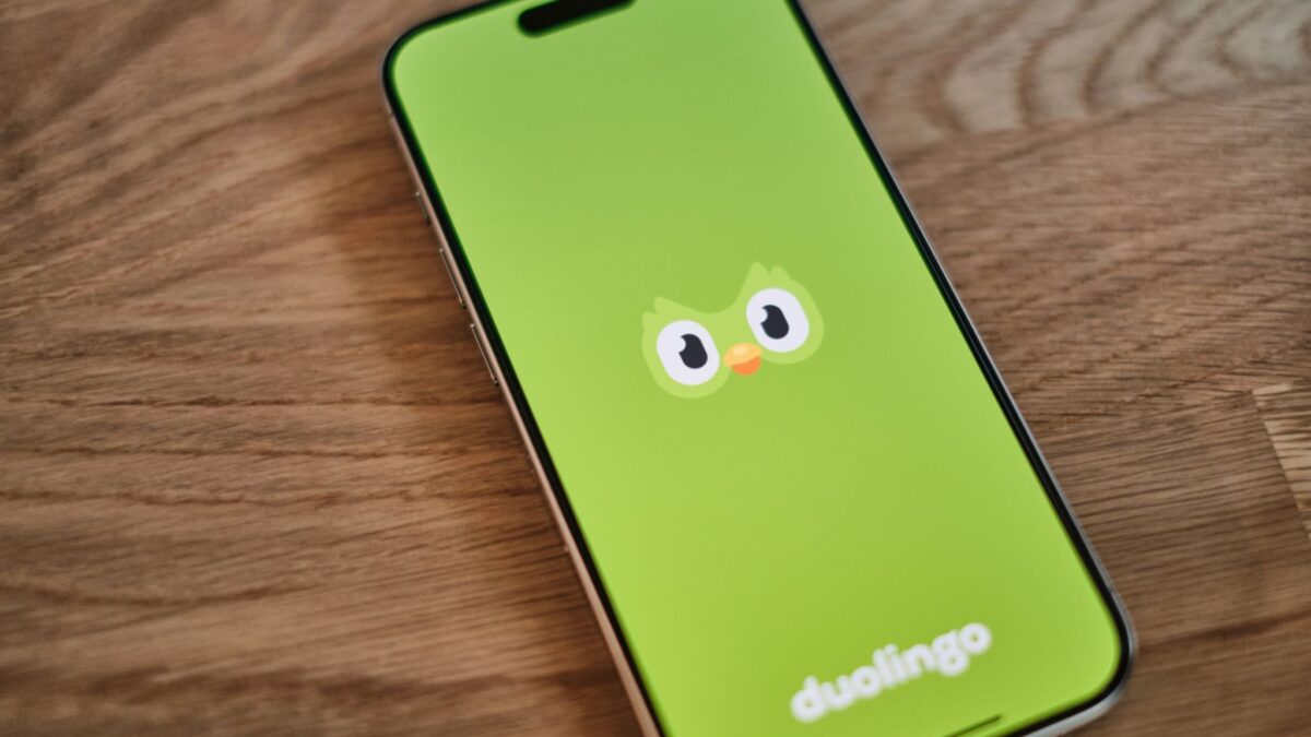 A phone with a green wallpaper with a Duolingo logo drawn on it