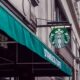 Exterior view of a Starbucks coffee shop in a city setting, featuring signage and awning.